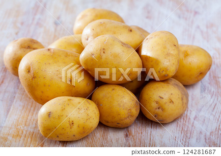 Pile of raw potatoes at wooden table in home kitchen 124281687