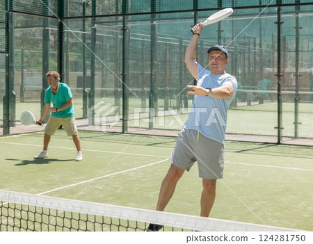 Padel game - man with partners plays on court 124281750