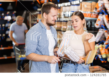 Married couple choose paint brush and paint roller together for their home renovation at hardware store Married couple choose paint brush and paint roller together for their home renovation at hardware store 124281785