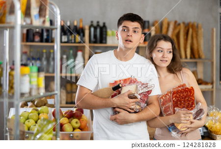 Cheerful couple shopping for gourmet meats, cheese, and wine in shop 124281828