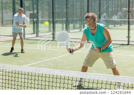 Men play padel on an outdoor tennis court. Hitting the ball with racket 124281844