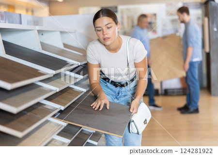 Young woman choosing laminate flooring sample Young woman choosing laminate flooring sample 124281922