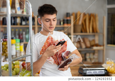 Young guy is scanning QR on dried sausage and meat in grocery store 124281932