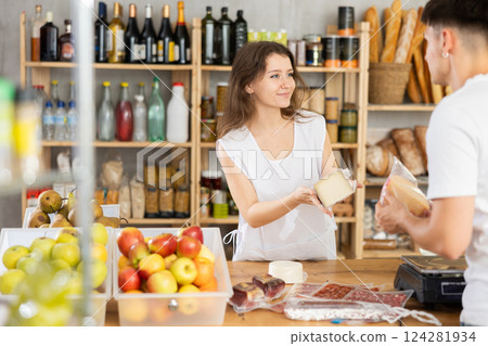 Young woman seller offers cheese to man Young woman seller offers cheese to man 124281934