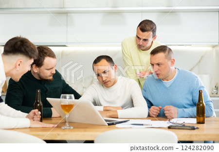 Men drink beer and try to help friend solve problems using laptop and Internet Men drink beer and try to help friend solve problems using laptop and Internet 124282090