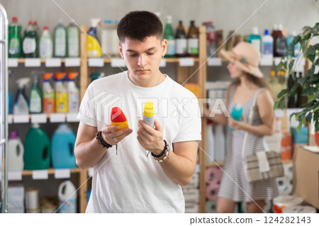 Guy view trademark sign on label, pick eco friendly mosquito repellent, woman shopping in background 124282143