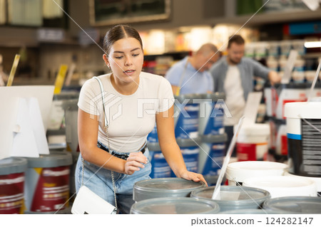 Girl examine bucket of paint, buy collect necessary supplies for renovation 124282147