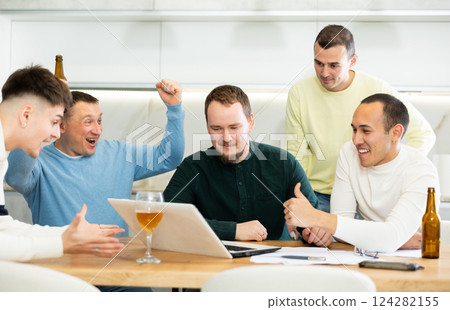 Men rejoicing over good news on laptop at home gathering 124282155