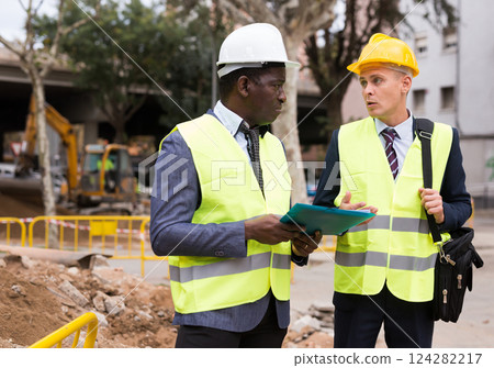 Two engineers talking about road repairing works documentation Two engineers talking about road repairing works documentation 124282217