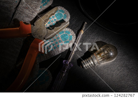 A burnt-out light bulb, a screwdriver, pliers and cloth gloves A burnt-out light bulb, a screwdriver, pliers and cloth gloves 124282767