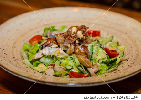 Salad with meat and nuts on a plate on a wooden Salad with meat and nuts on a plate on a wooden 124283134
