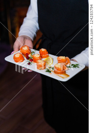 Appetizing fish rolls in the hands of a waiter on Appetizing fish rolls in the hands of a waiter on 124283794