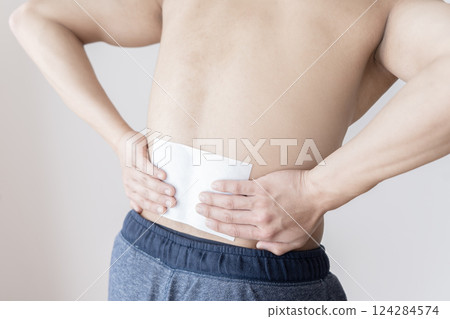 Man applying a compress to his lower back, lower back pain, compress, muscle pain 124284574
