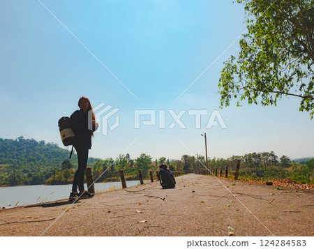 silhouette solo hiker woman walk on street with lake and forest background 124284583