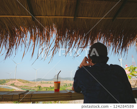 solo traveler man sit and drink coffee at counter bar with wind turbine background 124284589