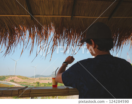 solo traveler man sit and drink coffee at counter bar with wind turbine background 124284590