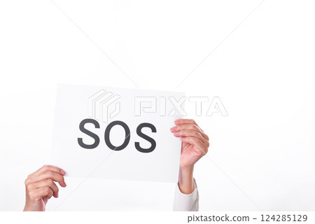 A hand holding up a piece of paper with the word SOS written on it 124285129