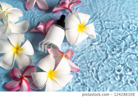 Moisturizing serum surrounded by fresh plumeria blooms creates a serene spa atmosphere. Moisturizing serum surrounded by fresh plumeria blooms creates a serene spa atmosphere. 124286108