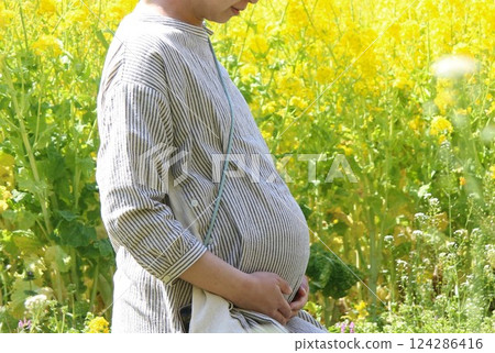 A pregnant woman in her final month gazing at rape blossoms 124286416