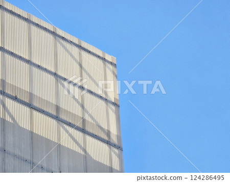 Sunlit on White Corrugated Metal of Modern Building with Blue Sky. Sunlit on White Corrugated Metal of Modern Building with Blue Sky. 124286495