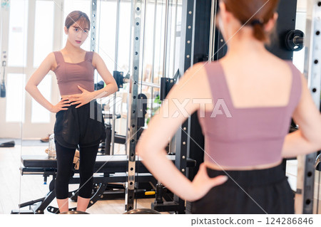 Young woman checking her figure at the gym 124286846