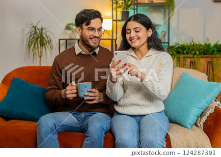 Happy girlfriend boyfriend couple browse social media applications together on smartphone at home 124287391