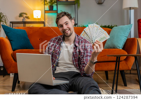 Rich happy Caucasian man counting money cash dollar using laptop calculate domestic bills at home Rich happy Caucasian man counting money cash dollar using laptop calculate domestic bills at home 124287394