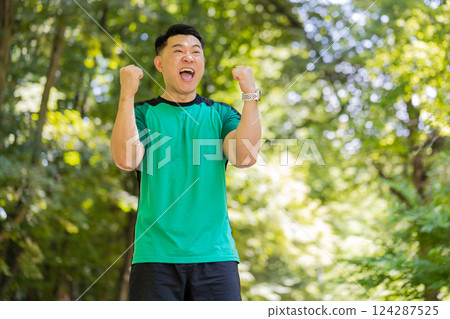 Asian athletic runner man celebrate success win rejoices triumph victory marathon race in park Asian athletic runner man celebrate success win rejoices triumph victory marathon race in park 124287525