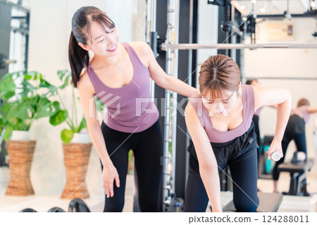 A woman receiving personal training from a female coach at the gym 124288011