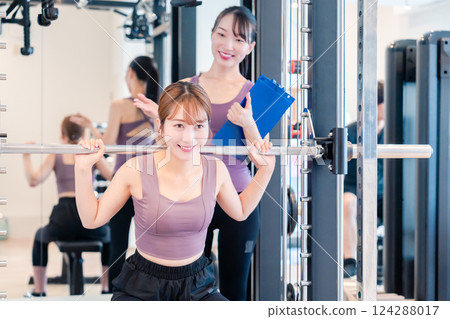 A woman receiving personal training from a female coach at the gym 124288017