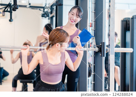 A woman receiving personal training from a female coach at the gym 124288024