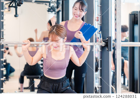 A woman receiving personal training from a female coach at the gym A woman receiving personal training from a female coach at the gym 124288031