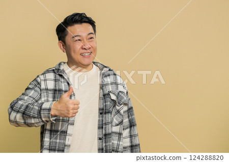 Asian man raises thumbs up agrees give positive reply recommends advertisement likes good idea 124288820