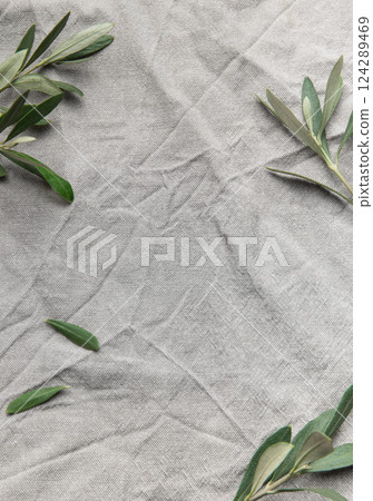 Olive branches framing wrinkled gray linen cloth background 124289469