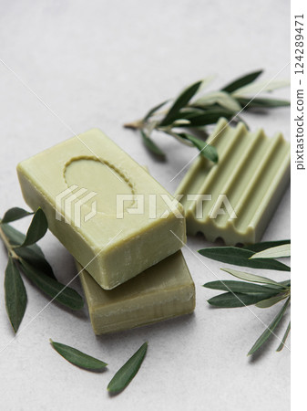 Olive soap bars resting on marble surface with olive branches Olive soap bars resting on marble surface with olive branches 124289471