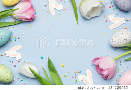 Easter eggs and tulips creating a frame on light blue background 124289485