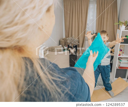 boy developing motor skills and coordination by playing on a wooden wobble board during a therapy session, interacting with a therapist boy developing motor skills and coordination by playing on a wooden wobble board during a therapy session, interacting with a therapist 124289537
