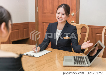 A woman meeting and signing a contract with a concierge, hotelier, and wedding planner (marriage agency) A woman meeting and signing a contract with a concierge, hotelier, and wedding planner (marriage agency) 124289755