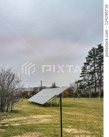 Solar Panel Installation in Rural Field, Overcast Sky, Renewable Energy, Sustainability, Natural Setting. High quality photo 124290716