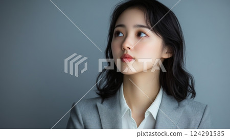 A dignified woman is thinking deeply in front of a gray background 124291585