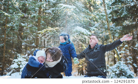 Happy family enjoying playful moments in the snow, surrounded by a stunning winter forest filled with trees and falling snowflakes Happy family enjoying playful moments in the snow, surrounded by a stunning winter forest filled with trees and falling snowflakes 124291870