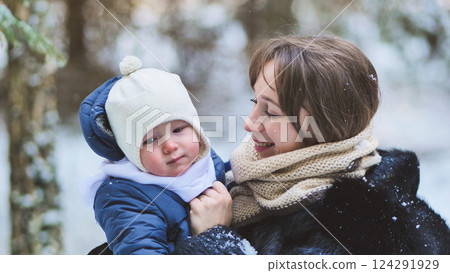 Loving mother cuddling infant among snow covered trees, sharing peaceful winter moment outdoors Loving mother cuddling infant among snow covered trees, sharing peaceful winter moment outdoors 124291929