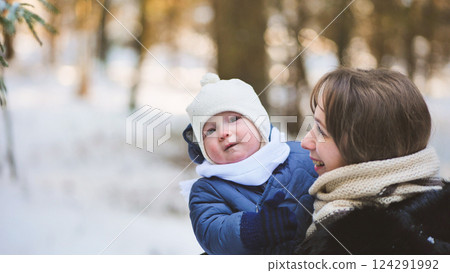 Happy mother holding her baby, enjoying a beautiful winter day surrounded by a serene snowy forest, creating joyful family memories Happy mother holding her baby, enjoying a beautiful winter day surrounded by a serene snowy forest, creating joyful family memories 124291992