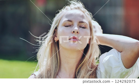 Blonde woman resting, sunlight caressing face, hand gently touching hair, radiating calm and relaxation Blonde woman resting, sunlight caressing face, hand gently touching hair, radiating calm and relaxation 124292075