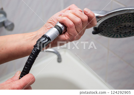 Woman changing broken shower hose in bathroom. Female plumber hands fixing hose. Plumbing concept. Male and female professions concept. Woman changing broken shower hose in bathroom. Female plumber hands fixing hose. Plumbing concept. Male and female professions concept. 124292905