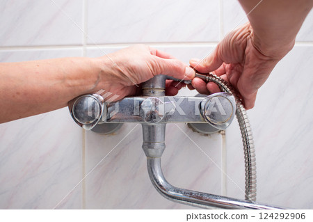 Woman changing broken shower hose in bathroom. Female plumber hands fixing hose. Plumbing concept. Male and female professions concept. 124292906