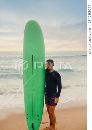 Surfer holding surf board on the beach at sunset. Happy man guy having fun doing extreme sport 124293063