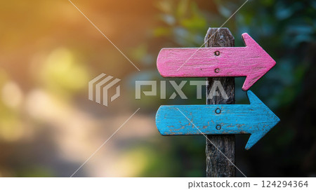 Two pink and blue arrow pointers on a pole in the park, pointing to the women's and men's toilets. 124294364