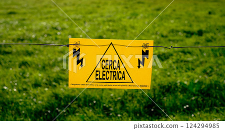 Warning sign on an electric fence with Spanish text Cerca Electrica meaning Electric Fence. Warning sign on an electric fence with Spanish text Cerca Electrica meaning Electric Fence. 124294985