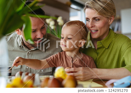 Family decorating easter eggs at home. 124295270